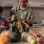 A family enjoys quality time in the kitchen, preparing a meal with fresh vegetables.