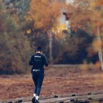 Person jogging on a wooden path surrounded by vibrant autumn foliage in Jönköping, Sweden.